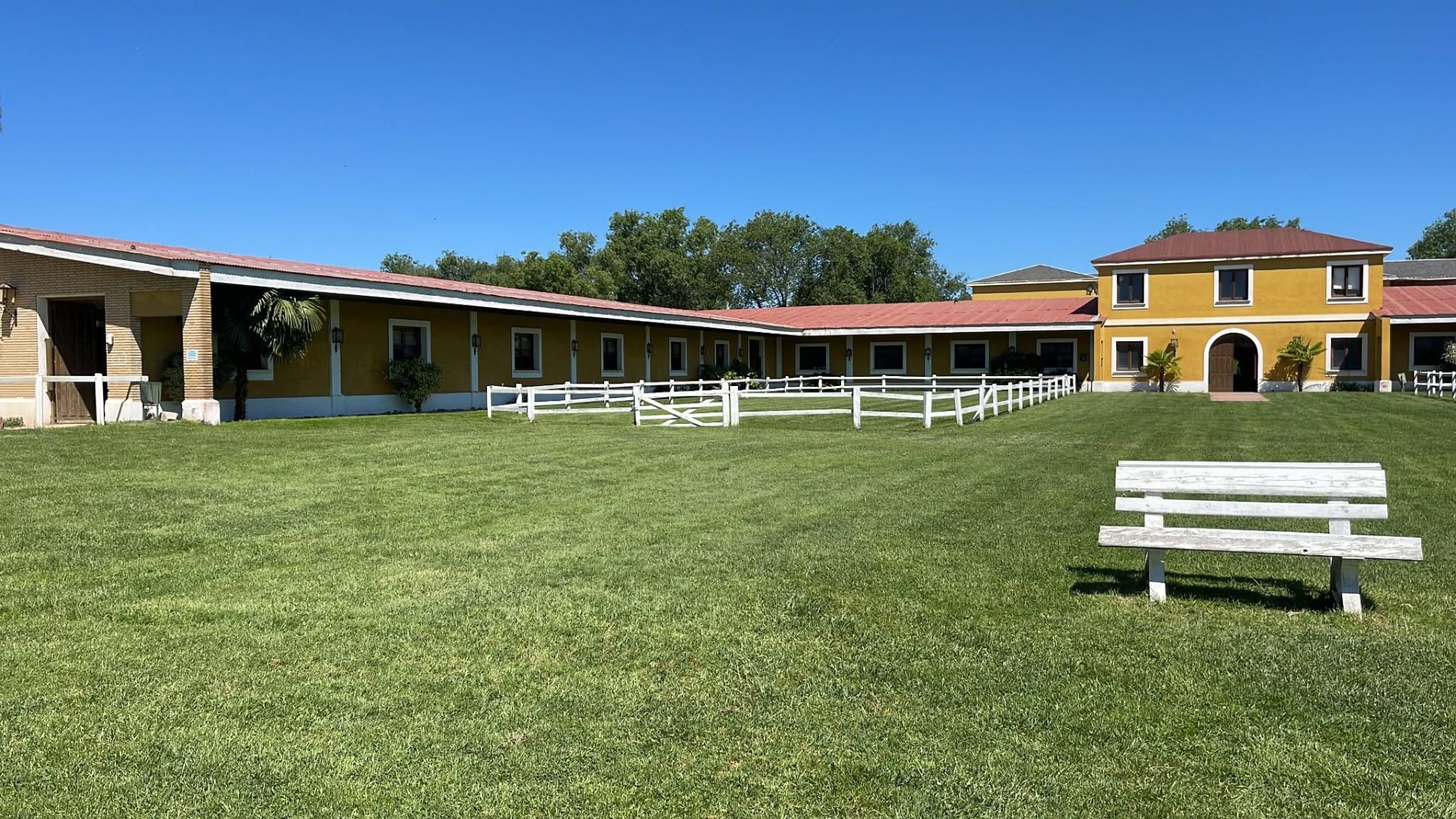 Vista panorámica de las instalaciones amarillas y el jardín de Club Hípico Yabusan